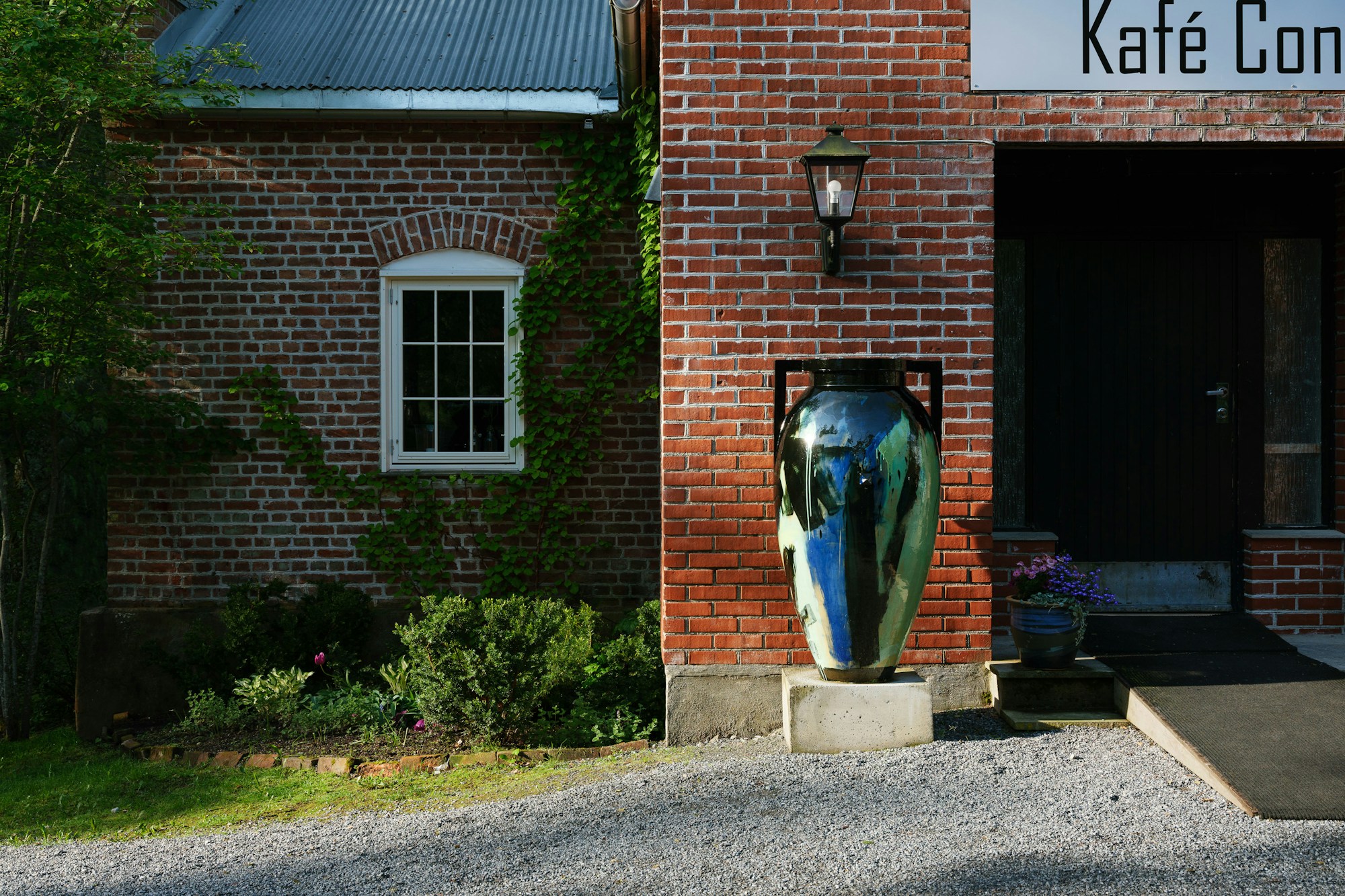 large scale jar in front of an old brick house