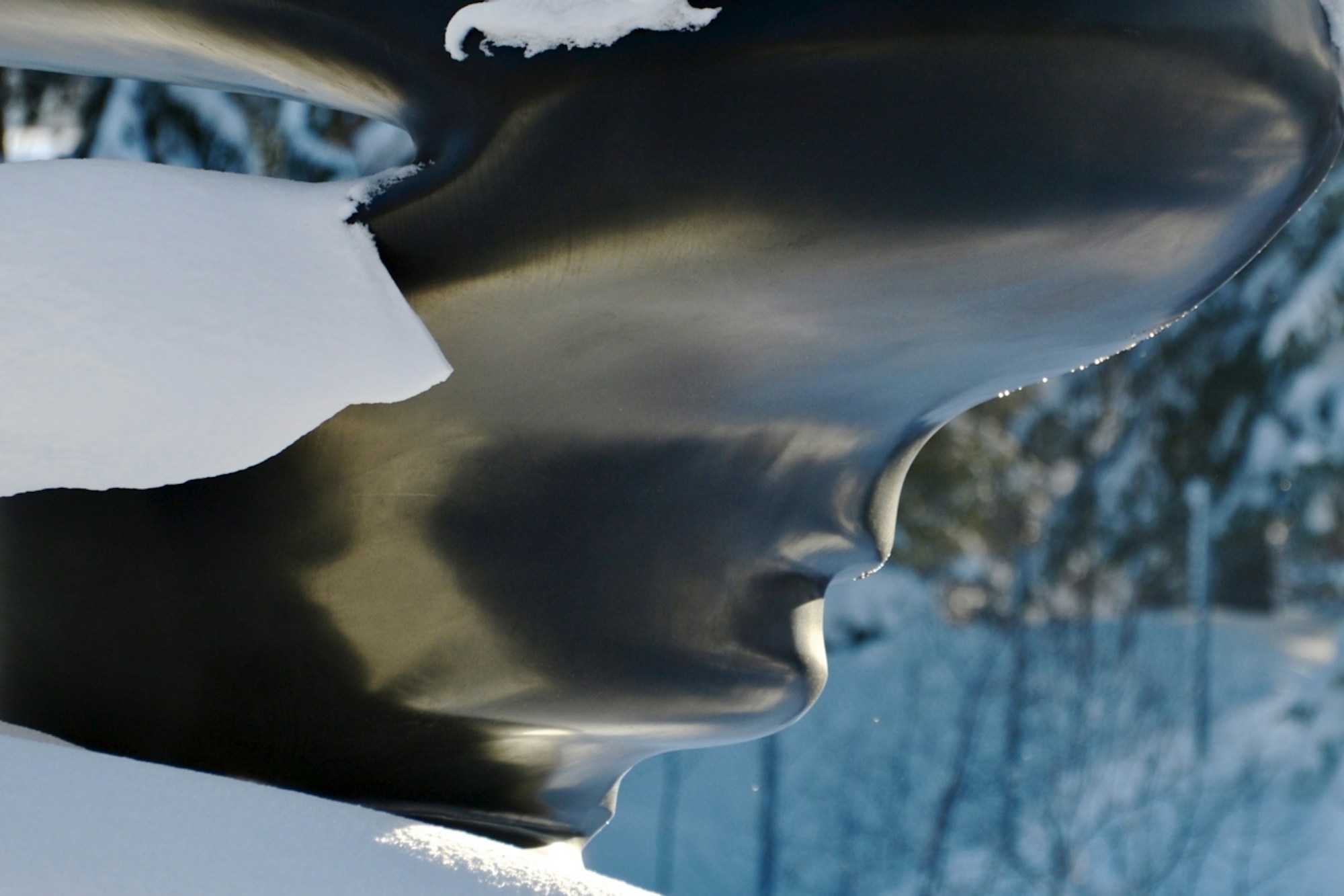 Detaljbilde av skulpturen Bent of Mind av Tony Cragg. Skulpturen er svart og den hvite snøen fungerer som en sterk kontrast.