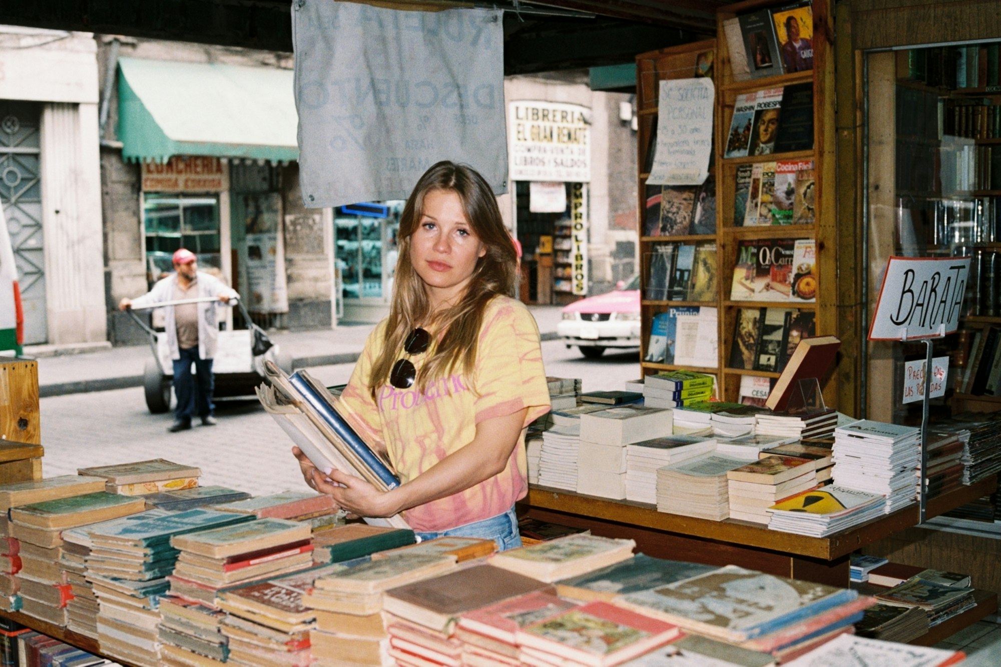 Portrett av kunstner Ida Ekblad. Jente med langt lyst hår holder bøker i en gammel bokhandel.