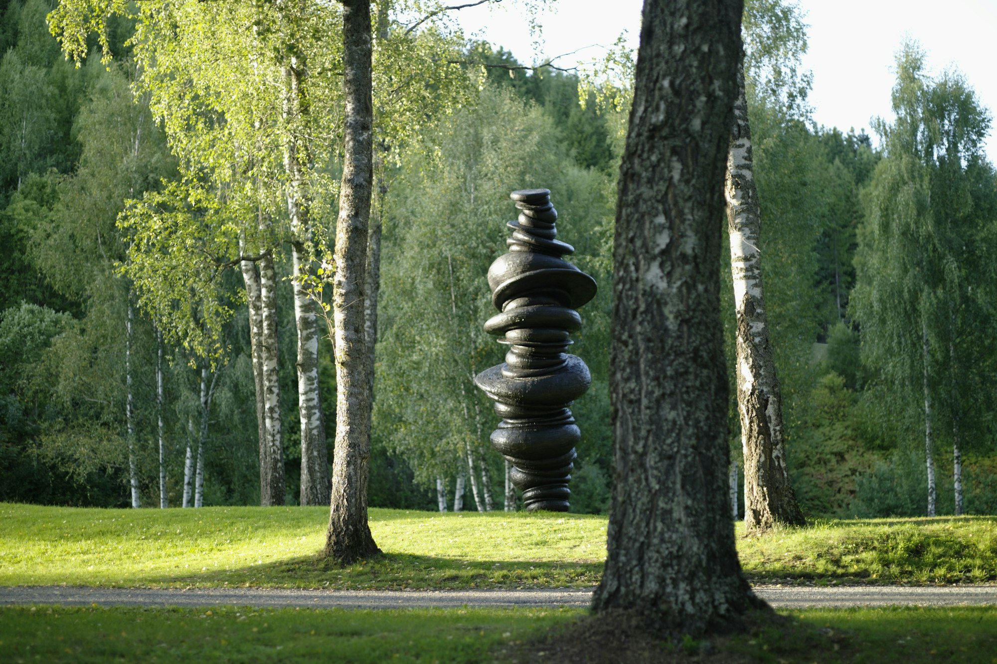 Sculpture, black, stones placed on top of each other. Nature, green.